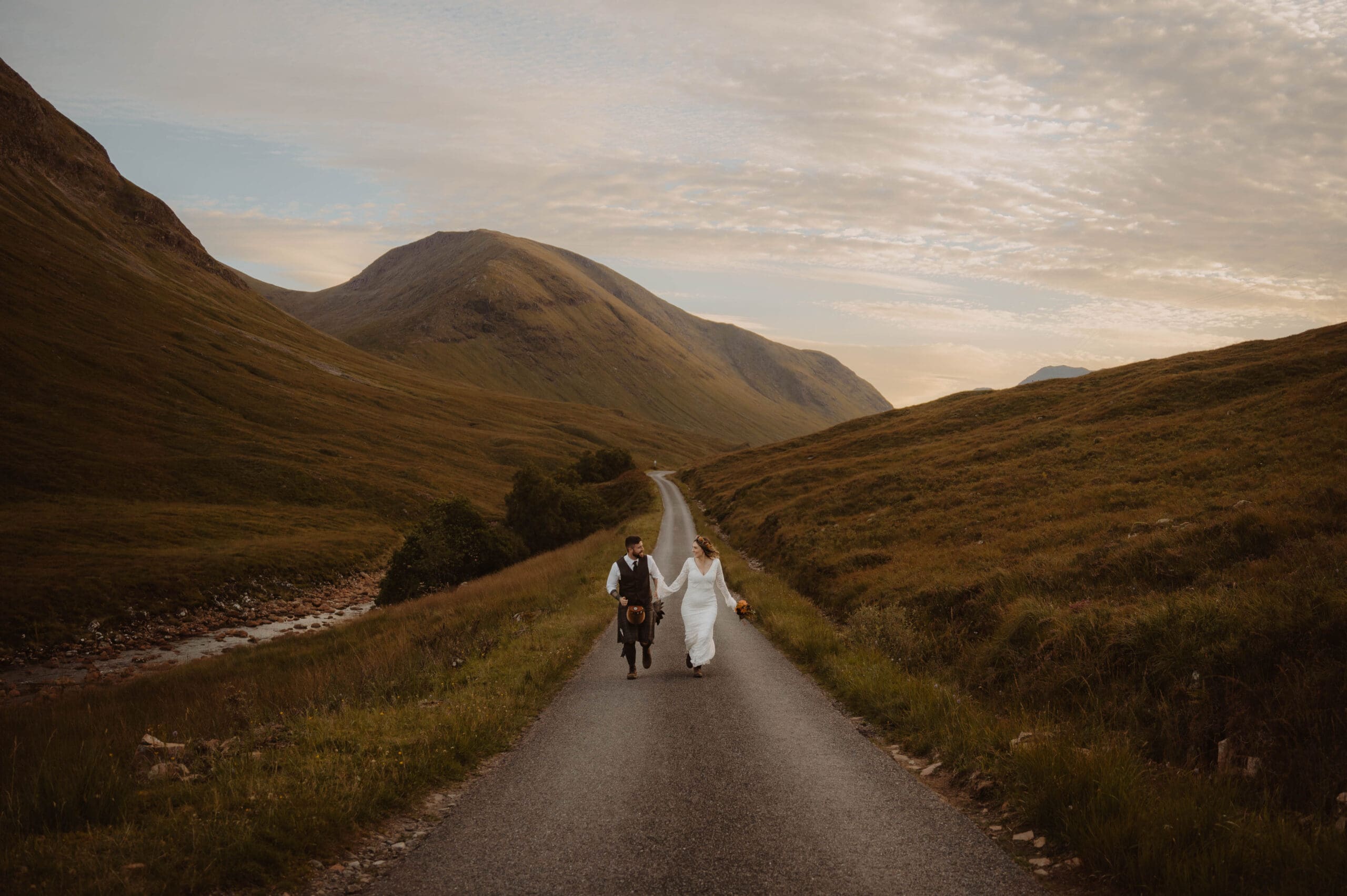 couple running in glen etive, glencoe on their elopement day scottish highlands